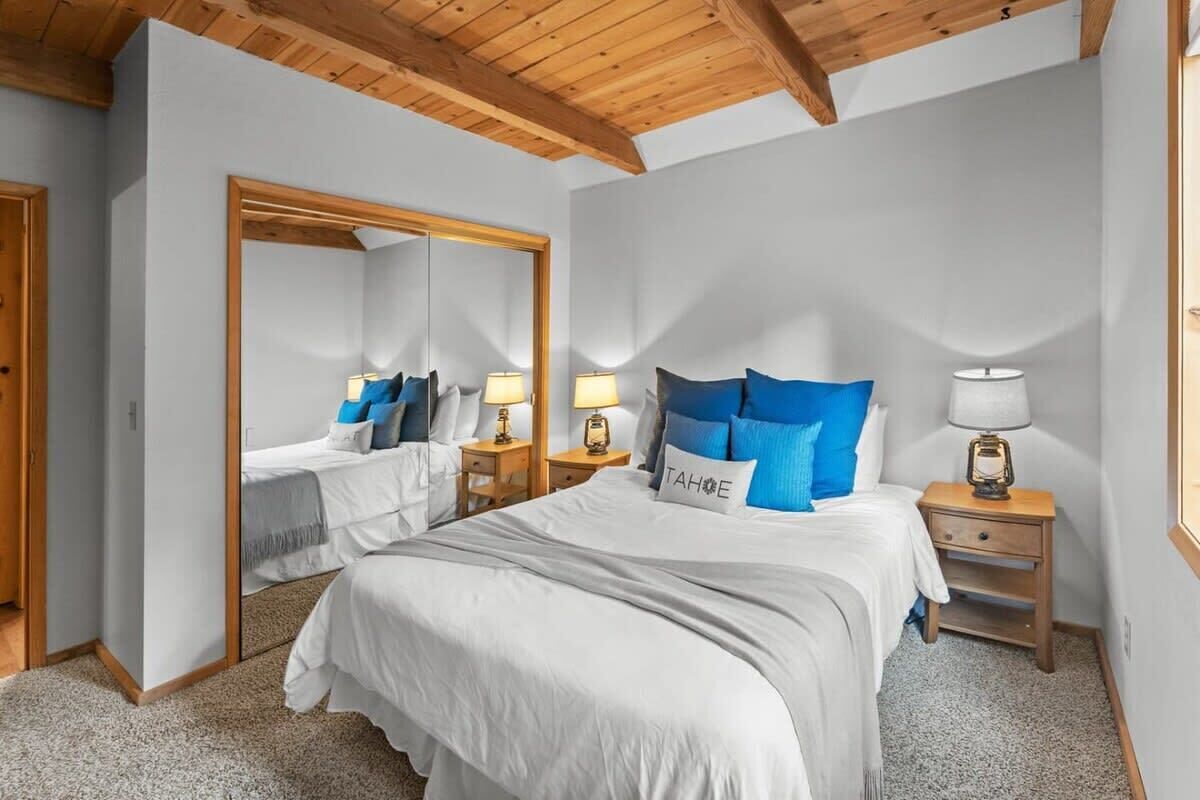 A bedroom with a large bed, two bedside tables with lamps, a mirror, and a door.