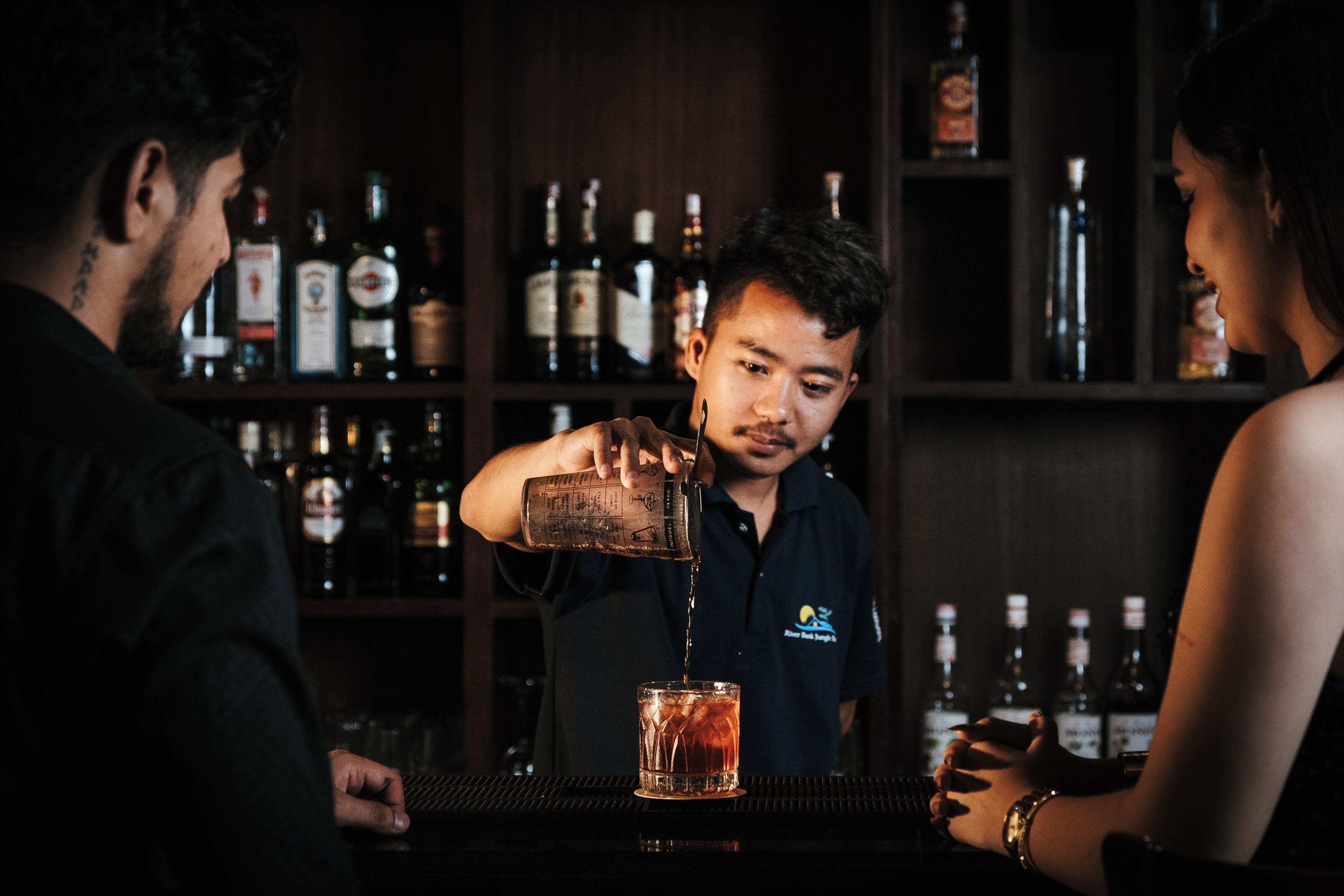 Un bar con un barman sirviendo una bebida en un vaso.