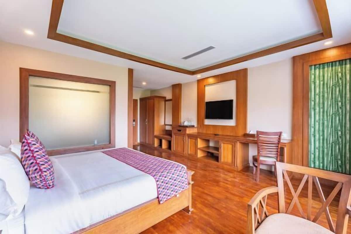 Une chambre d’hôtel avec un lit, un bureau, une chaise et un grand miroir.