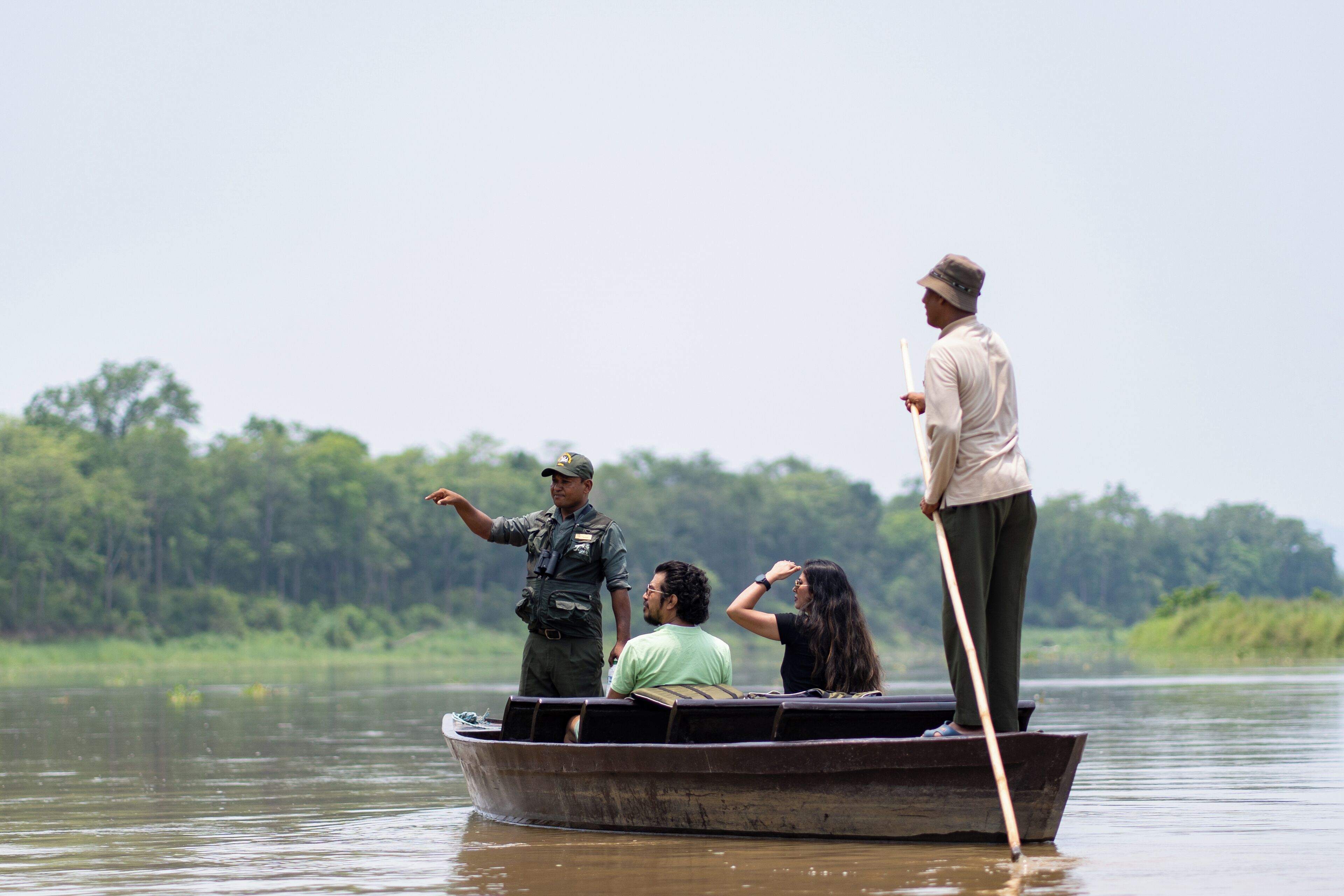 A small boat with three people on a calm body of water, surrounded by greenery.