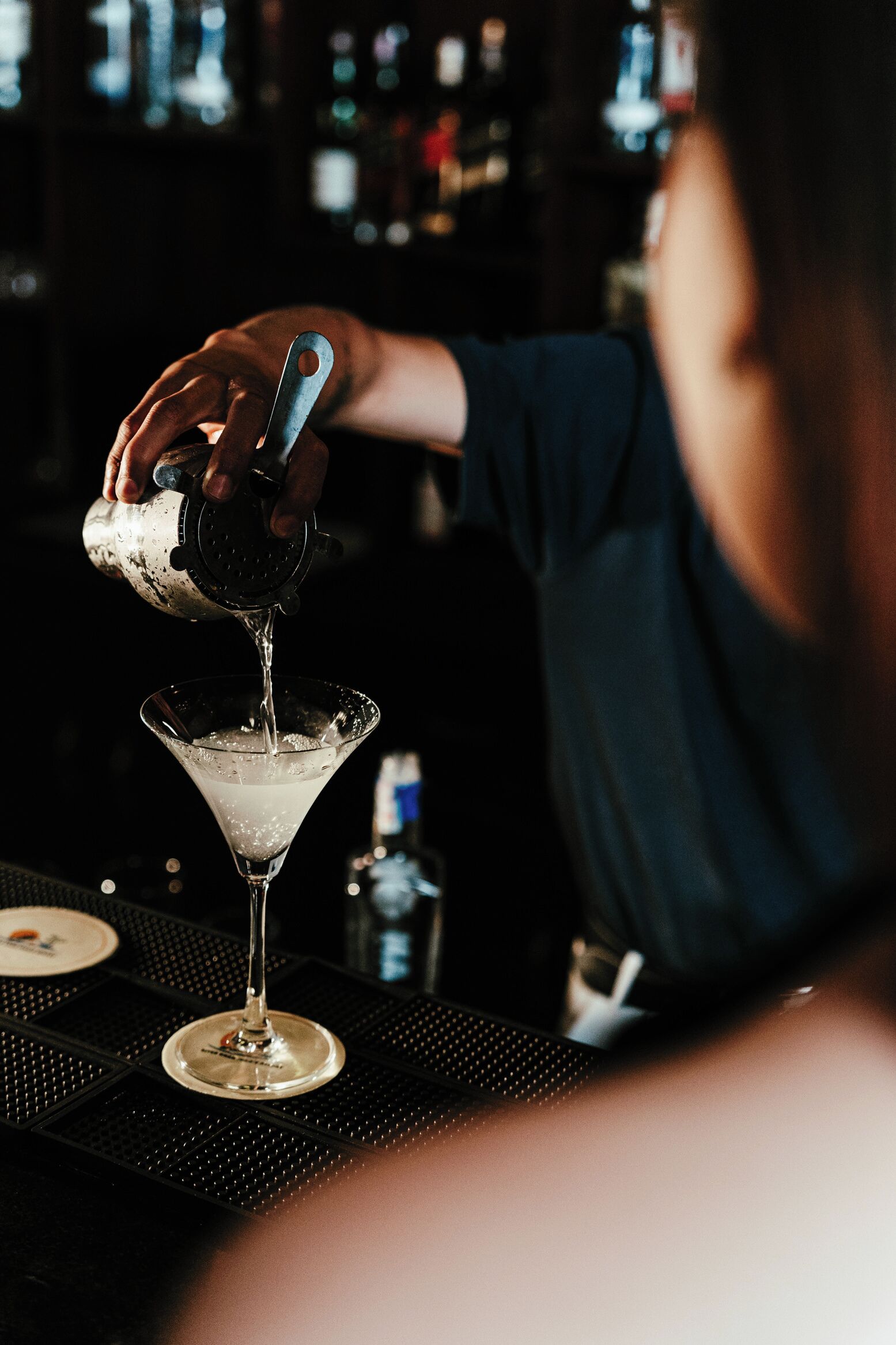 Een barman schenkt een drankje in een martini-glas.
