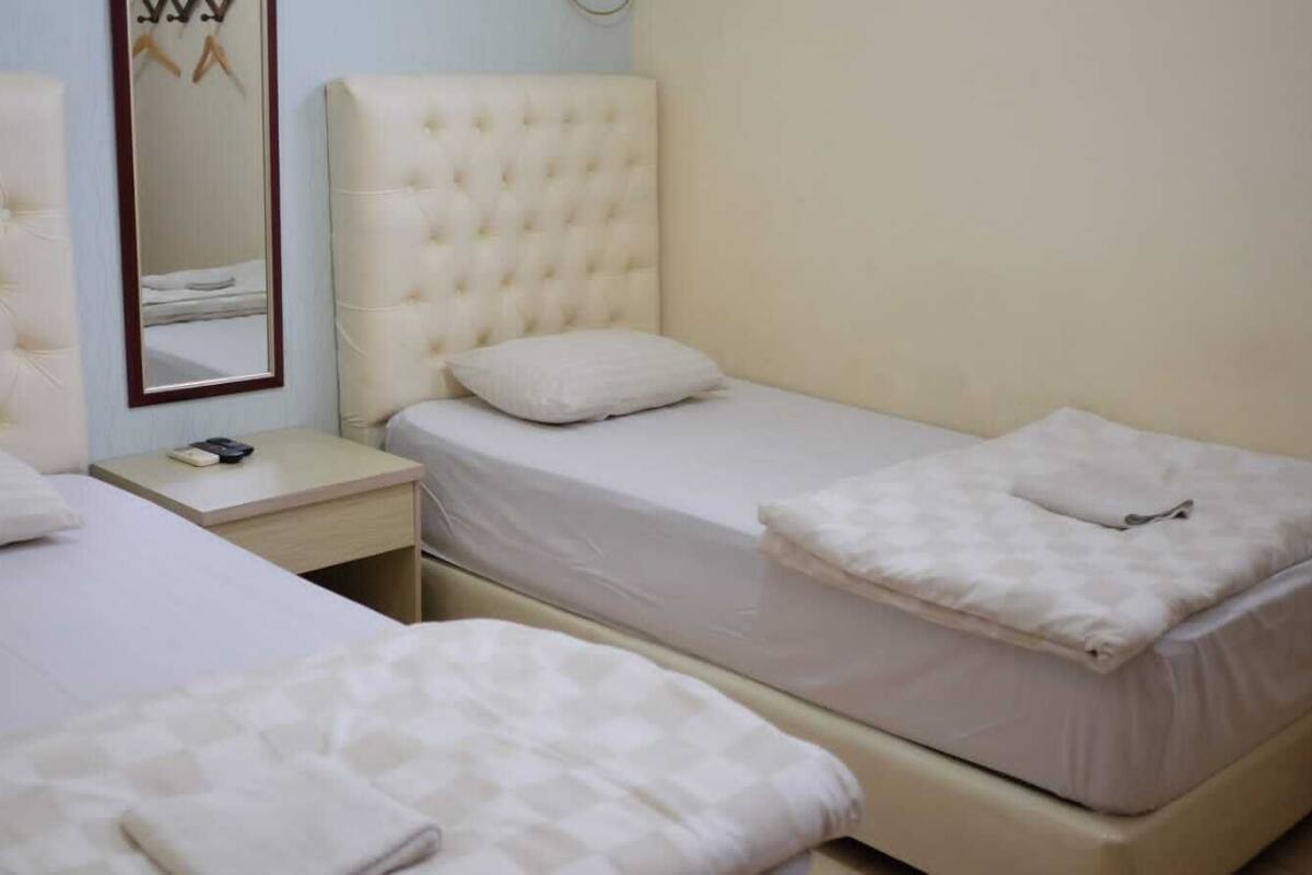 A bedroom with two beds, a nightstand, and a mirror.