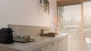 A modern kitchen with a coffee maker, a sink, and a vase with flowers. - Studio Loet Schagen (Schagen)