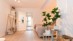 A modern bedroom with a bed, a small table, a chair, a wardrobe, and a potted plant. - Studio Loet Schagen (Schagen)