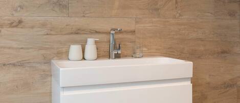 A bathroom with a white vanity, a mirror, and a wooden wall.