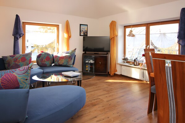 A living room with a sofa, a television, and a dining area with a table and chairs.