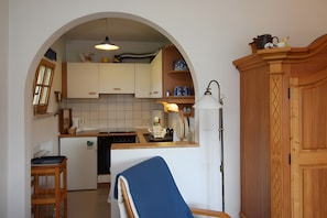 A compact kitchen with an arched doorway, a small dining area, and a wooden cabinet.