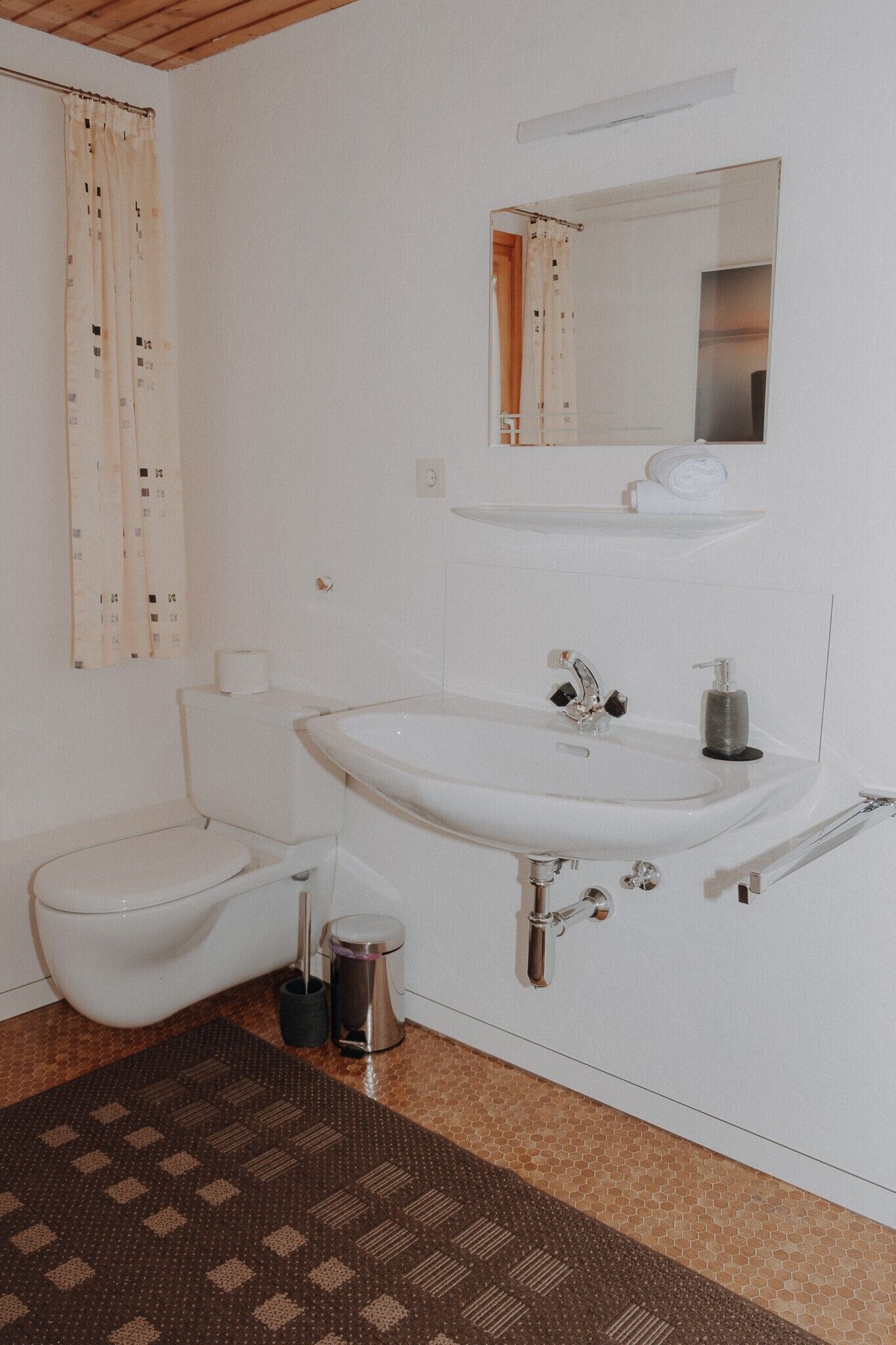 A bathroom with a toilet, sink, mirror, and shower curtain.