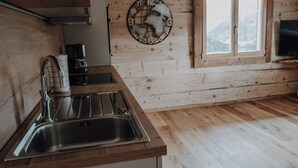 Une cuisine avec un intérieur en bois, un évier en acier inoxydable, une machine à café et une horloge murale.