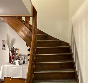 A wooden staircase with a white wall and a table with various items.