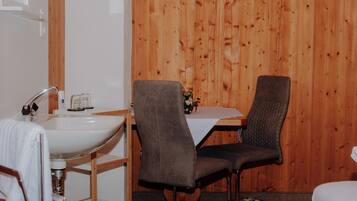 A bathroom with a sink, two chairs, and a wooden wall.