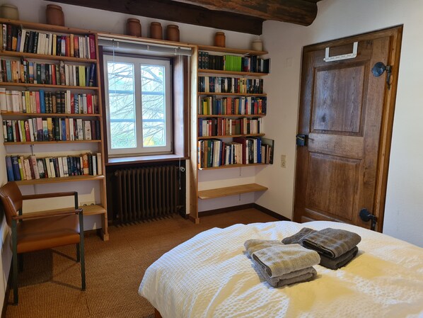 A cozy room with a large bed, a chair, and multiple bookshelves filled with books.