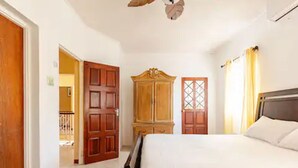 Une chambre à coucher avec un lit, une armoire en bois et une porte donnant sur une autre pièce.