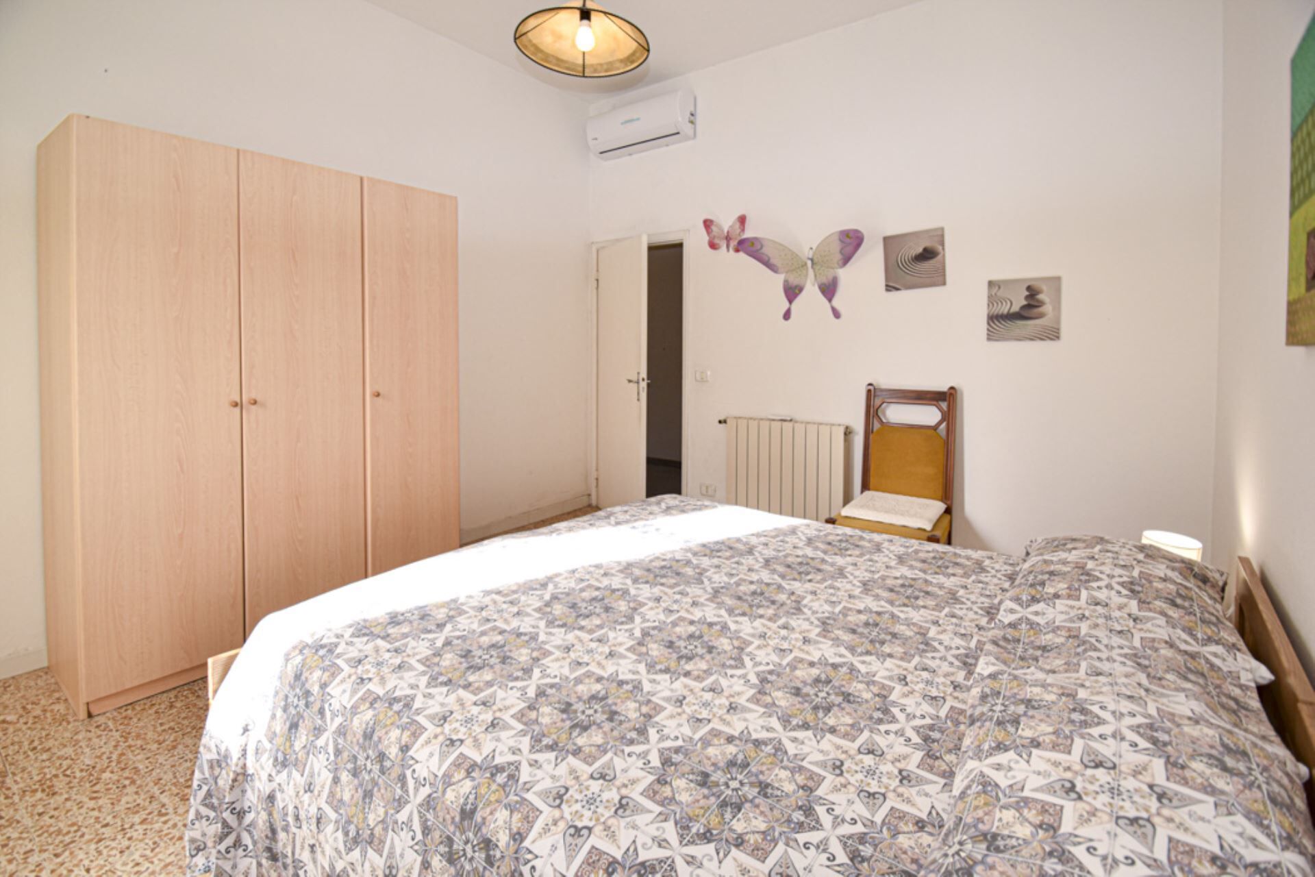 A bedroom with a bed, a wardrobe, a radiator, and wall art.