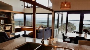 A modern kitchen with a large island, granite countertops, and a view of a lake.