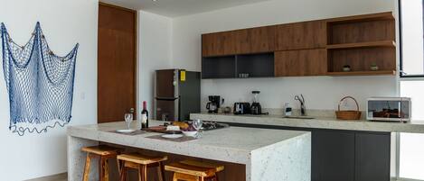 A modern kitchen with a large island, wooden bar stools, and built-in appliances.