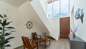 Una habitación amplia con techo inclinado, muebles de madera, un reloj decorativo en la pared y vistas a través de una ventana.