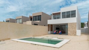 Un edificio residencial moderno con piscina, terraza cubierta y pared de piedra.