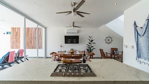 Una cocina moderna con estufa a gas, ventiladores de techo y un comedor con muebles de madera.