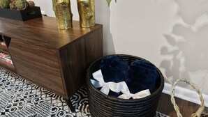 Een moderne kamer met een donkerhouten console en een geweven mand met blauwe kussens, plus een kamerkleed met een patroon.
