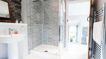A modern bathroom with a glass shower, white sink, and stone wall.