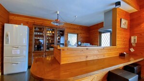 A modern kitchen with wooden cabinetry, a built-in refrigerator, and a bar area with stools.
