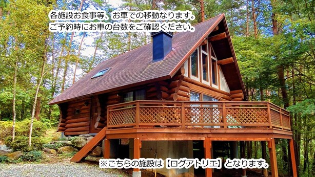A log cabin with a balcony, surrounded by trees.