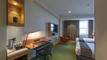 A hotel room with a bed, a desk with a chair, a television, and a minibar.
