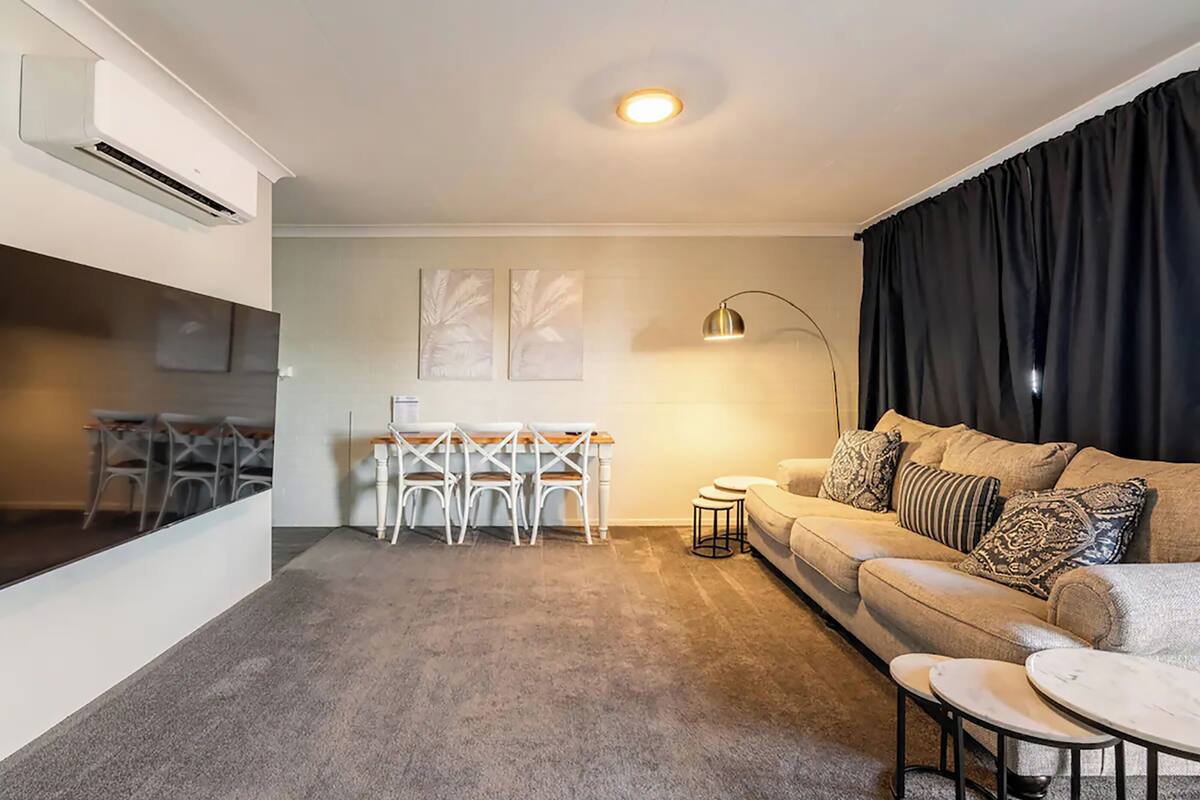 Un salon moderne comprenant un canapé, une table basse et un coin repas avec une table et des chaises.