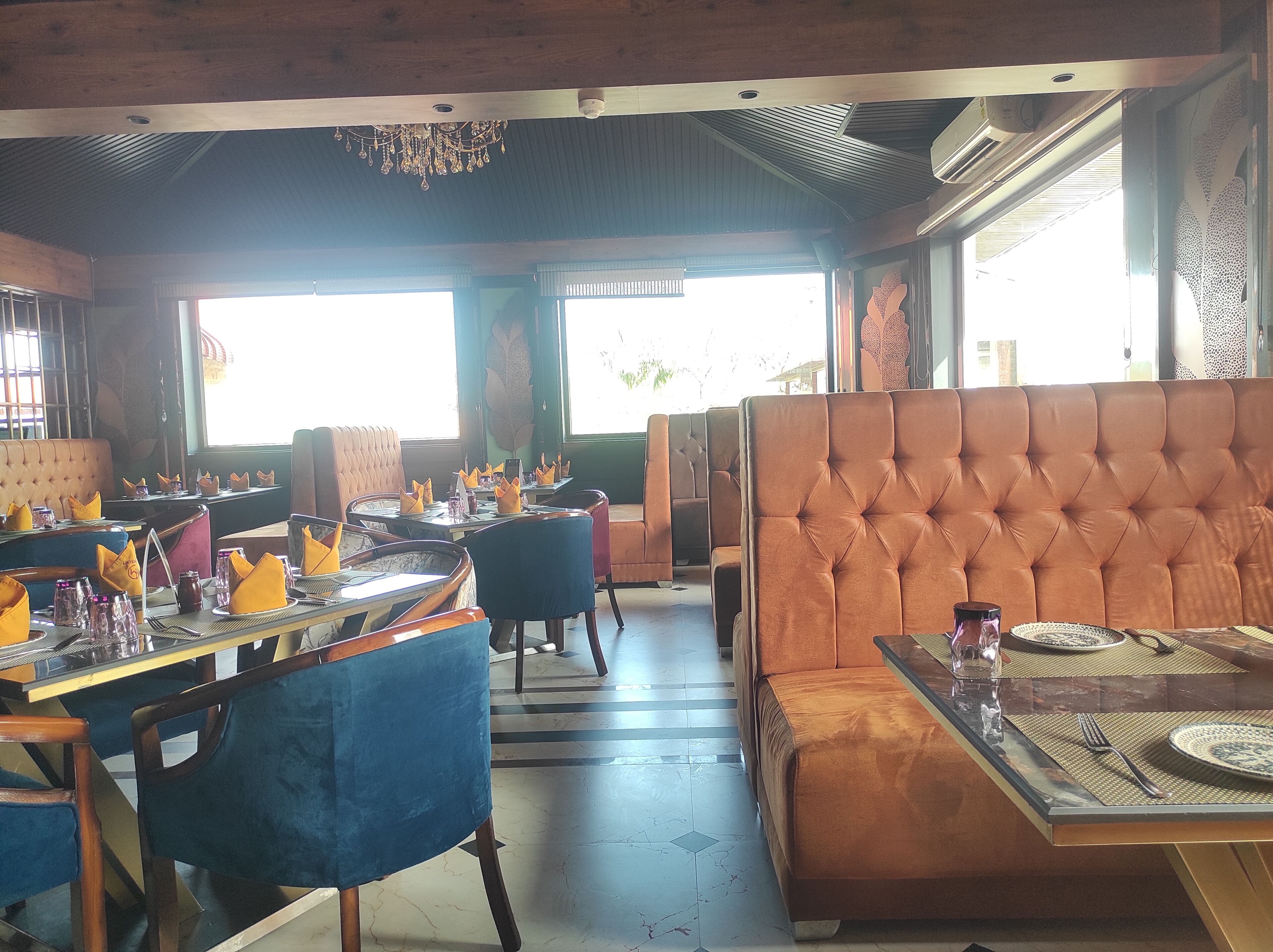 A restaurant with booths and tables, wooden ceiling, and large windows.