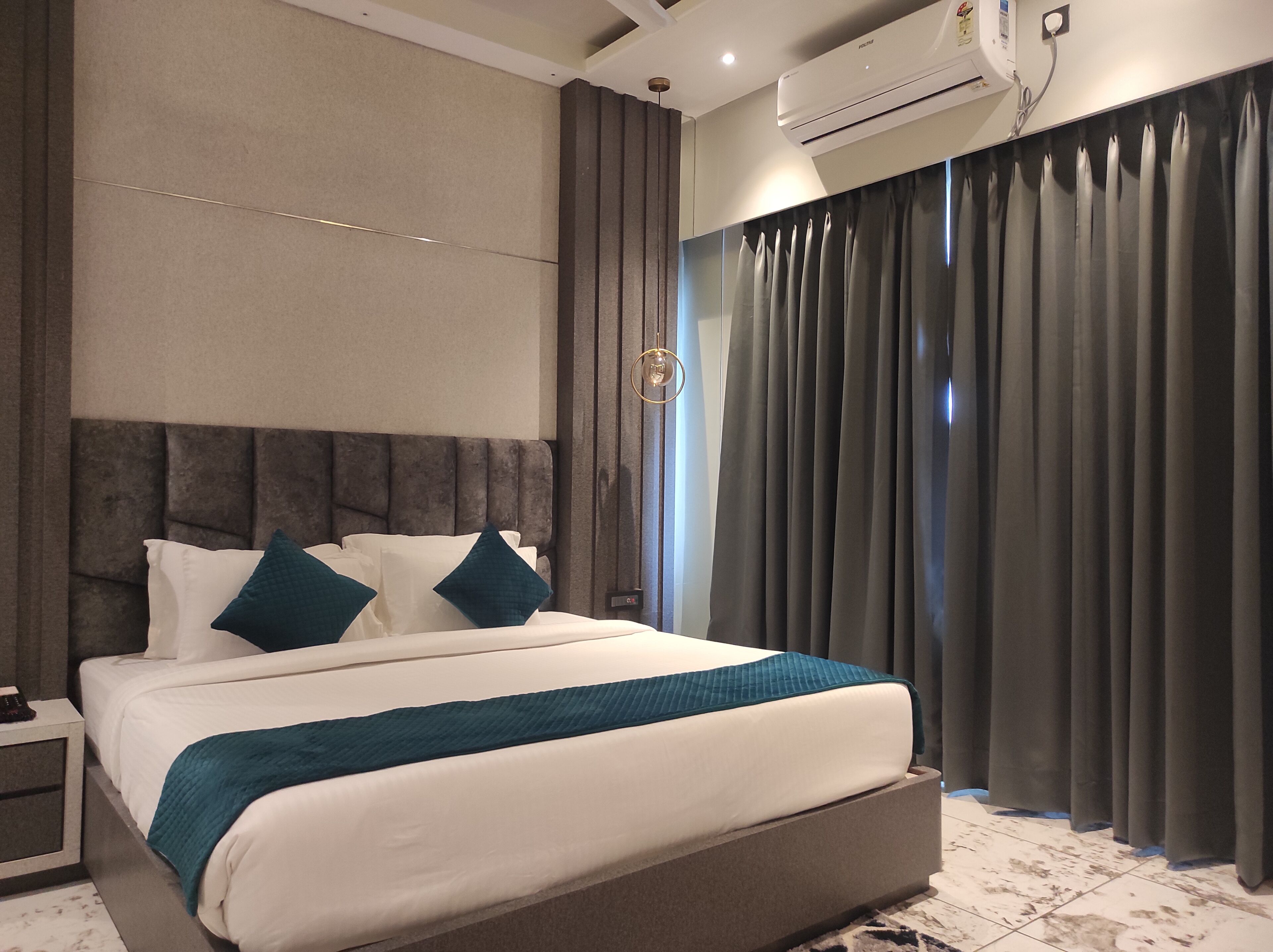 A modern bedroom with a large bed, a headboard, a nightstand, and a wall-mounted air conditioner.
