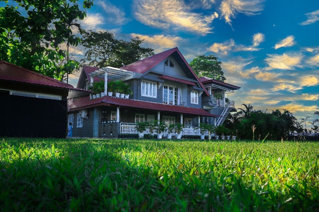 A two-story house with a red roof, white trim, and a balcony.