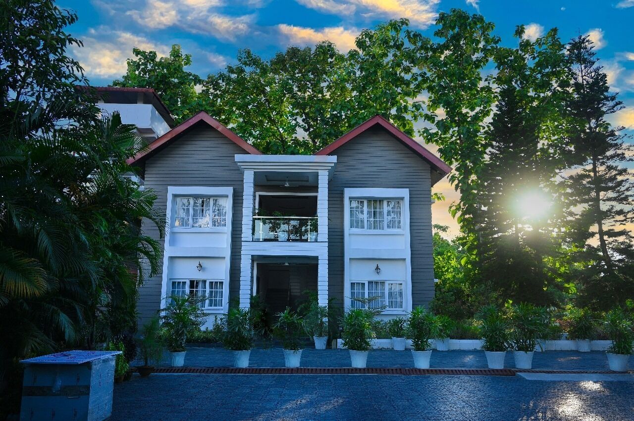 Une maison à deux étages avec une entrée centrale, entourée d’une végétation luxuriante et dotée d’une allée pavée.