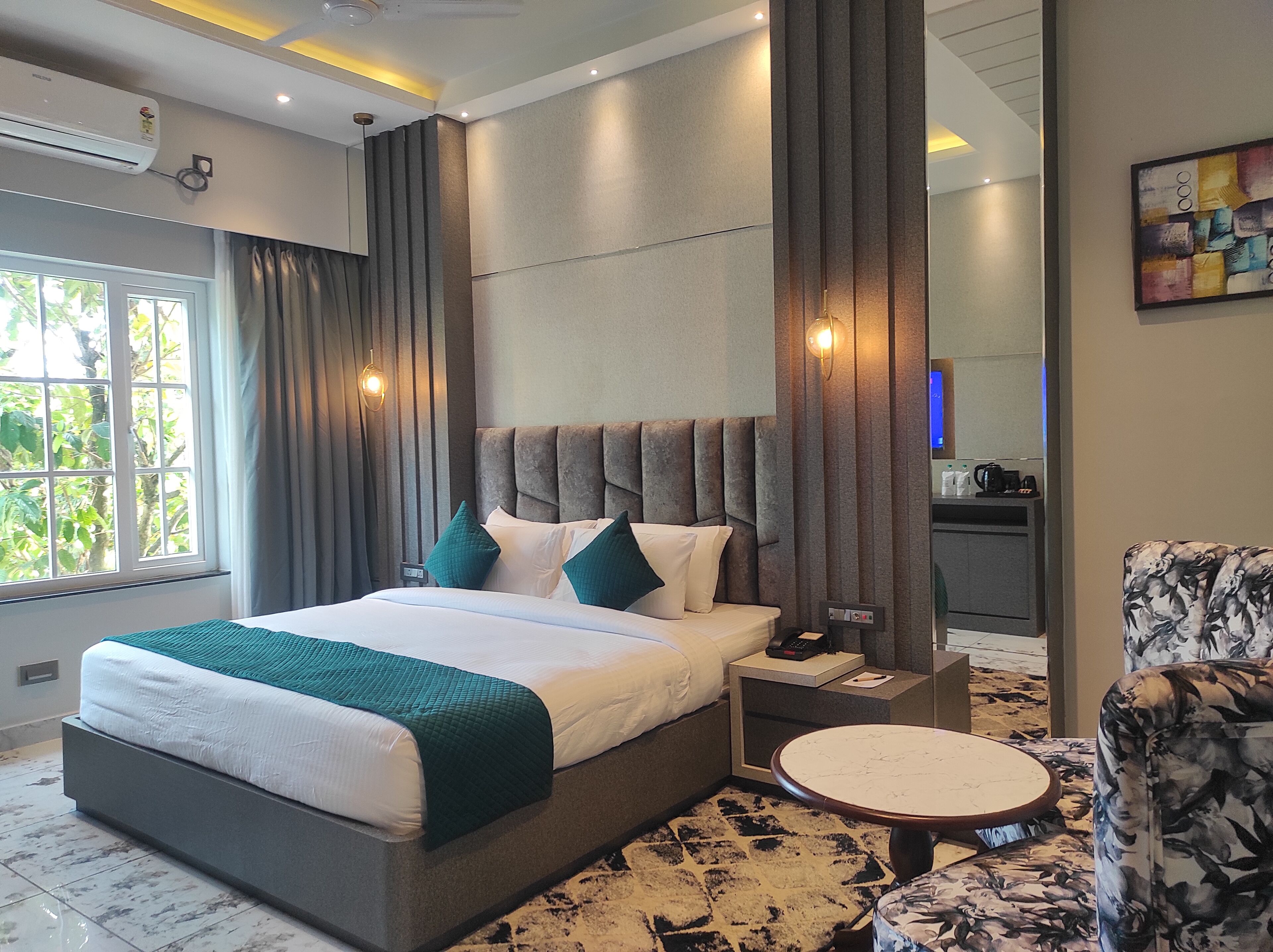 Una habitación de hotel moderna con una cama grande, una mesita de noche, una mesa redonda y una silla.