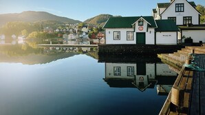 A waterfront building with a green roof, a sign reading "MANDAGHUSSET," and a dock extending into calm water. - Heggland Huset by Interhome (Tysnes)