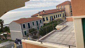Un immeuble résidentiel avec un toit recouvert de tuiles, un balcon doté d’une rambarde en métal et une vue sur la mer.