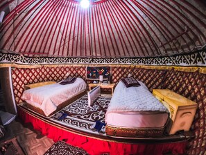 A traditional yurt with two beds, a small table, and a heater. - Karkyra glamping (Karkara)