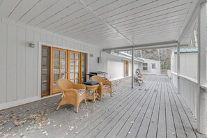 A covered porch with wicker chairs and a table, wooden deck, and a small building in the background. - Home Near Lincoln National Forest w/ Private Sauna (Cloudcroft)