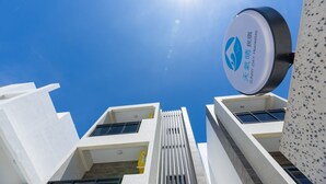 A modern building with a clear blue sky and a sign indicating a 'Sunny Day Homestay'. - Sunny Day Homestay (Magong)
