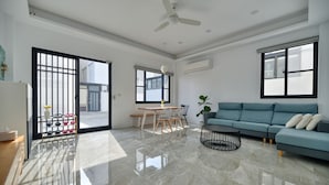 A spacious living area with a blue sofa, a dining table with chairs, and a ceiling fan. - Sunny Day Homestay (Magong)