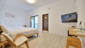 A modern hotel room with a bed, a desk with a chair, a TV, and a window with curtains. - Sunny Day Homestay (Magong)