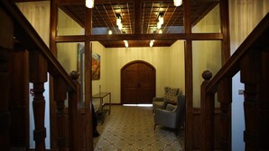 Una scala conduce a una stanza con una moquette decorata, una porta in legno e una sedia.