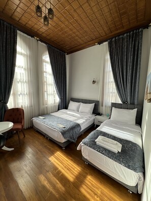Ein Hotelzimmer mit zwei Betten, einer Holzbalkendecke und einem kleinen Tisch mit Stuhl.