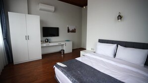 Una camera d'albergo con un letto, una scrivania, un armadio, una televisione e un condizionatore.