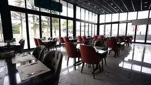 Un ristorante spazioso con ampie finestre, arredamento moderno e un pavimento pulito e lucido.