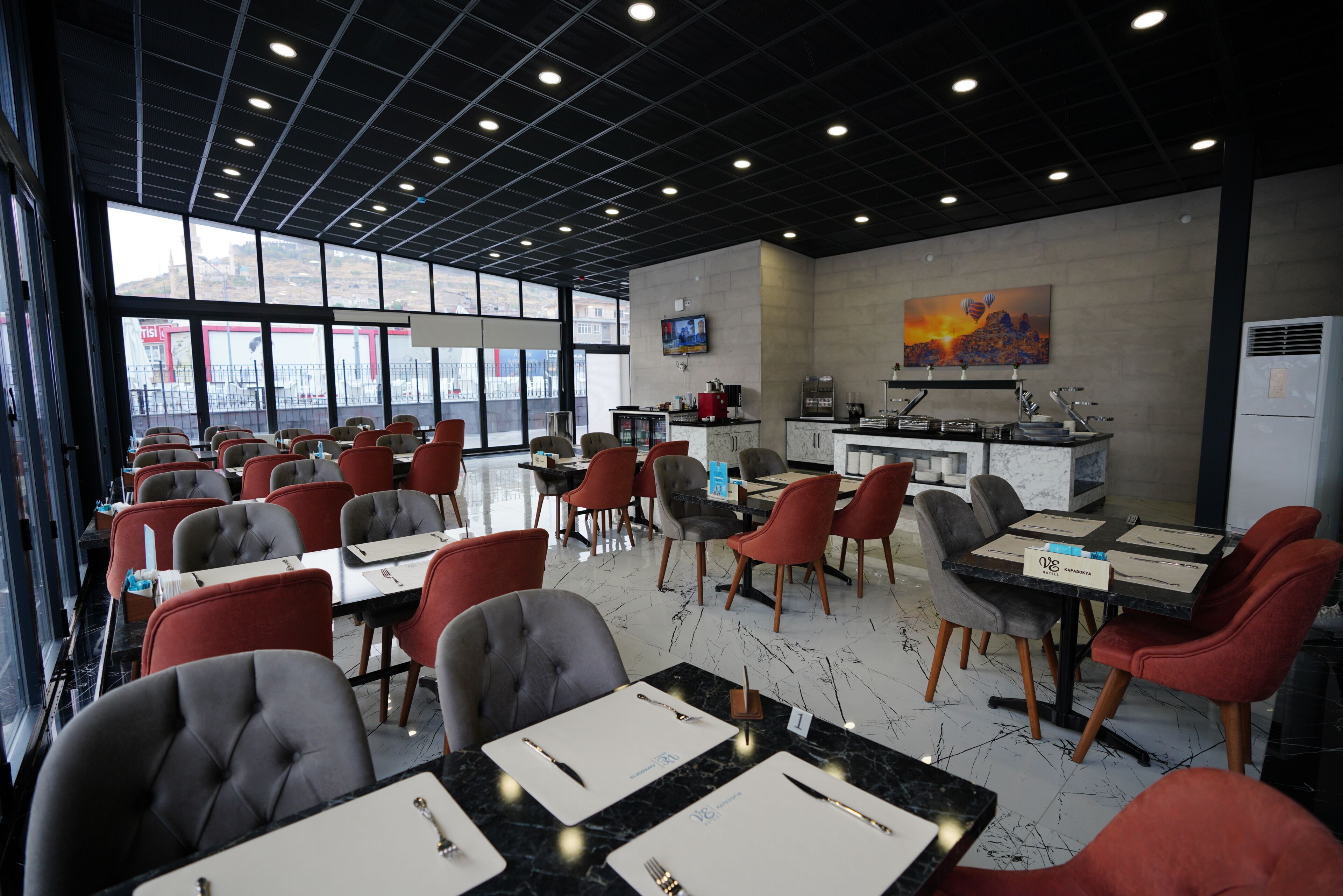 A restaurant with tables and chairs, a kitchen area, and a large window.