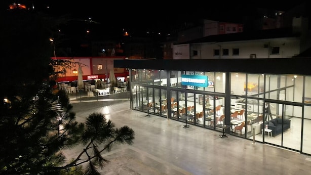 Un edificio moderno con facciata in vetro, insegna di un ristorante e posti a sedere all'aperto.