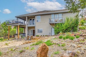 A two-story house with a balcony, outdoor seating, and a landscaped garden.