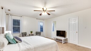 Un dormitorio con cama, ventilador de techo, televisor y escritorio.