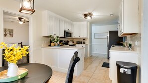 Una cocina moderna con armarios blancos, una isla central, un microondas y un fregadero.